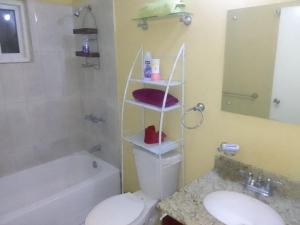 a bathroom with a toilet and a sink and a tub at Simpson's residence in Lucea