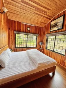 a bedroom with a bed with wooden walls and windows at Nhà An Cozy in Da Lat