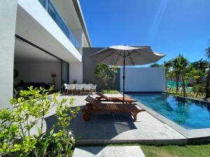 una sombrilla y un banco junto a una piscina en VILLA 4 BEDROOMS SANCTUARY HO TRAM Private Pool 5 STARS, en Thuận Biên