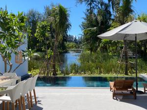 una piscina con mesa y sillas y una sombrilla en VILLA 4 BEDROOMS SANCTUARY HO TRAM Private Pool 5 STARS, en Thuận Biên