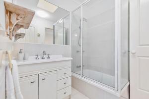 a white bathroom with a shower and a sink at Terrapin Apartment 4 in Noosaville