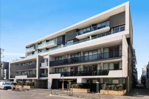 a white apartment building with balconies and a parking lot at Bayside Melbourne Apartment in Melbourne