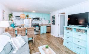 a living room with blue cabinets and a kitchen at Seaward Escape - Cherry Grove Beach in Myrtle Beach