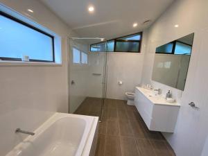 a bathroom with a tub and a sink and a mirror at ELEGANT LUXURY, STUNNING SEA VIEWS-see whales pass in Avoca Beach
