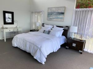 a bedroom with a large bed with white sheets and pillows at ELEGANT LUXURY, STUNNING SEA VIEWS-see whales pass in Avoca Beach