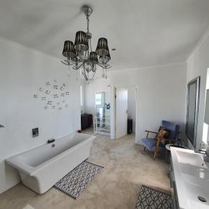baño blanco con bañera y lámpara de araña en Atlantic Loft - Open plan apartment with Sea Views, en Melkbosstrand