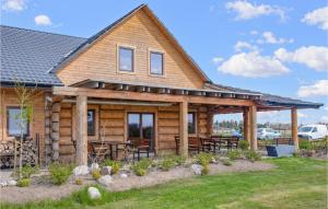 una cabaña de madera con mesas y sillas frente a ella en Cozy Home In Jezierzany With Sauna, en Jezierzany