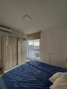 Un dormitorio con una gran cama azul y una ventana en Departamento San Luis Centro en San Luis