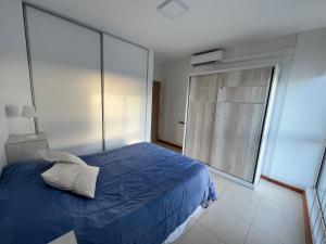 1 dormitorio con cama azul y ventana grande en Departamento San Luis Centro en San Luis