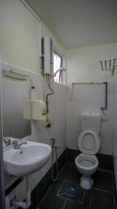 a bathroom with a white toilet and a sink at Hotel Citra in Brinchang