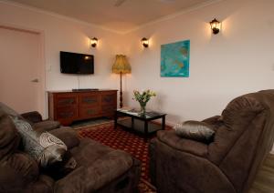 sala de estar con 2 sillas y TV de pantalla plana en Hill Cottage Hahndorf en Hahndorf
