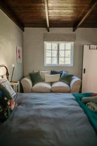ein Wohnzimmer mit einem Sofa und einem Bett in der Unterkunft Classic Greyton Cottage for Two in Greyton