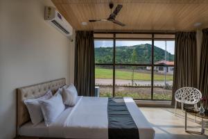 a bedroom with a bed and a large window at HillRock Resort & Villas, Neral-Karjat in Karjat +58 photos