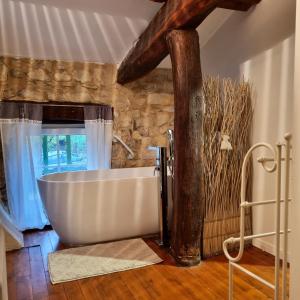 una gran bañera blanca en una habitación con ventana en Villa de 3 chambres avec piscine privee jacuzzi et jardin clos a Lussana, en Lussan