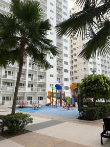 a playground in front of a building with palm trees at Yam Staycation Shore Residences in Manila