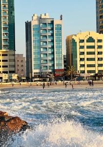 een strand met hoge gebouwen en mensen in het water bij Mermaid Beach Hotel LLC in Ajman 