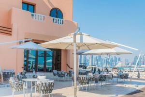 un patio con mesas, sillas y sombrillas en Mina Hotel and Residences, en Doha