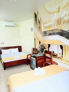 Cette chambre d'hôtel comprend deux lits, une table et des chaises. dans l'établissement Tay Dai Duong Guesthouse, à Hai Phong