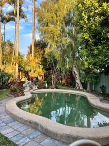 a swimming pool in a garden with palm trees at Comfortable Beach Home Scarborough in Scarborough