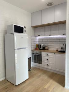 Il comprend une cuisine blanche équipée d'un réfrigérateur et d'un four micro-ondes. dans l'établissement Beautiful Guesthouse in Monbulk, à Monbulk