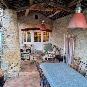 Habitación con mesa, sillas y pared de piedra. en Villa de 3 chambres avec piscine privee jacuzzi et jardin clos a Lussana, en Lussan