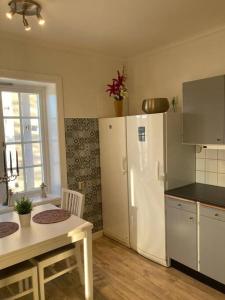 a kitchen with a table and a white refrigerator at Entire Town House on Ground floor front of Lake in Märsta
