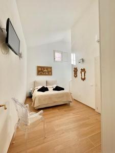 a white bedroom with a bed and a chair at Home Viale Trento 16 in Cagliari