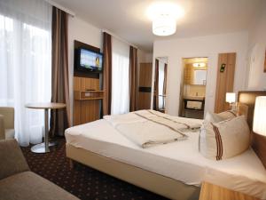 ein Hotelzimmer mit einem Bett und einem TV in der Unterkunft Hotel Diana in Pörtschach am Wörthersee