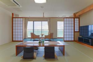 sala de estar con mesa, sillas y TV en Sayan Terrace Hotel & Resort, en Onjuku
