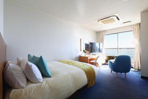 a hotel room with a bed and a desk and a window at Sayan Terrace Hotel & Resort in Onjuku