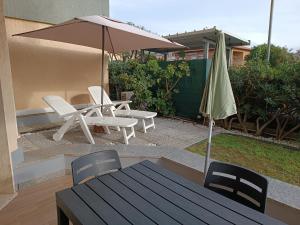 eine Terrasse mit einem Tisch, einem Sonnenschirm und Stühlen in der Unterkunft Casetta alla Spiaggia Ventimiglia in Ventimiglia