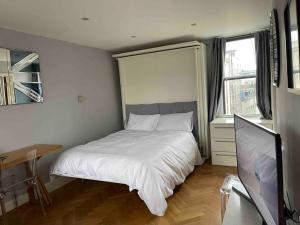 a bedroom with a bed and a desk and a television at Amazing apartment central London near tube station in London