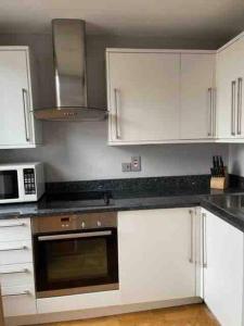 a kitchen with white cabinets and a microwave at Amazing apartment central London near tube station in London