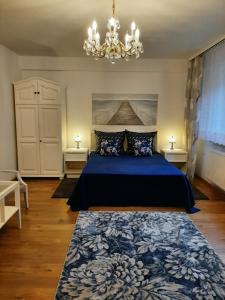 a bedroom with a blue bed and a chandelier at Blisko morza in Jastarnia