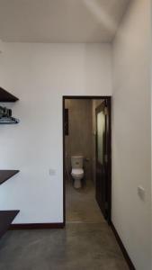 a bathroom with a toilet in a room with a doorway at Arazo villa in Unawatuna