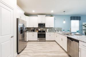 a kitchen with white cabinets and stainless steel appliances at Champions Gate Resort, Game Room, Theater, Miles From Disney! in Davenport