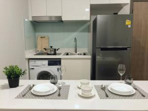 a kitchen with a table with plates and wine glasses at Modern style room with sky pool 古城边天际泳池公寓 in Chiang Mai