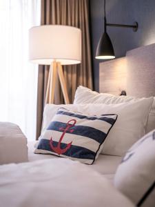 Una cama con una almohada con ancla roja. en Hotel Wehrburg, en Cuxhaven