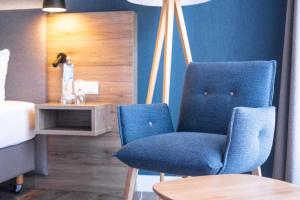 a bedroom with a blue chair and a table at Hotel Wehrburg in Cuxhaven