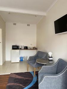 a living room with two chairs and a table and a tv at The Frontier Motel in Dorrigo