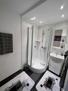 uma casa de banho branca com um chuveiro e um lavatório. em Apartment 1 Gäste em Schörfling