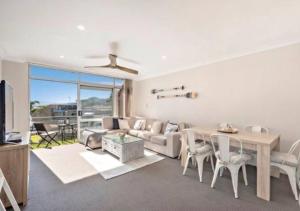 a living room with a table and a couch at Sparkling water views over Shoal Bay beach in Shoal Bay