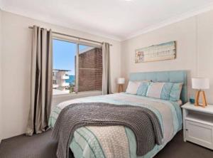 um quarto com uma cama e uma grande janela em Sparkling water views over Shoal Bay beach em Shoal Bay