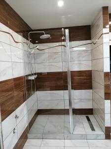 a shower with wooden walls and a glass door at Apartmán West in Poprad