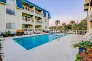 a swimming pool in front of a building with chairs at Oceanside 308-B in Isle of Palms