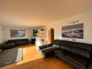 uma sala de estar com sofás de couro preto em Woodyard em Piesendorf
