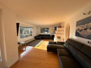 a living room with a leather couch and a window at Woodyard in Piesendorf