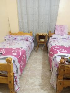 a bedroom with two beds and a chair at HORUS Nubian Guest House in Aswan