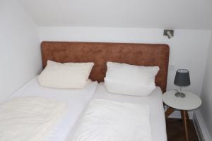 a bed with white sheets and pillows next to a table at Haus Fischer in Norderney