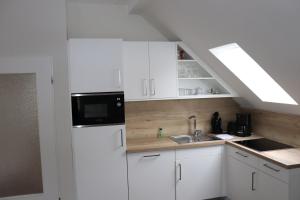 a white kitchen with a sink and a refrigerator at Haus Fischer in Norderney